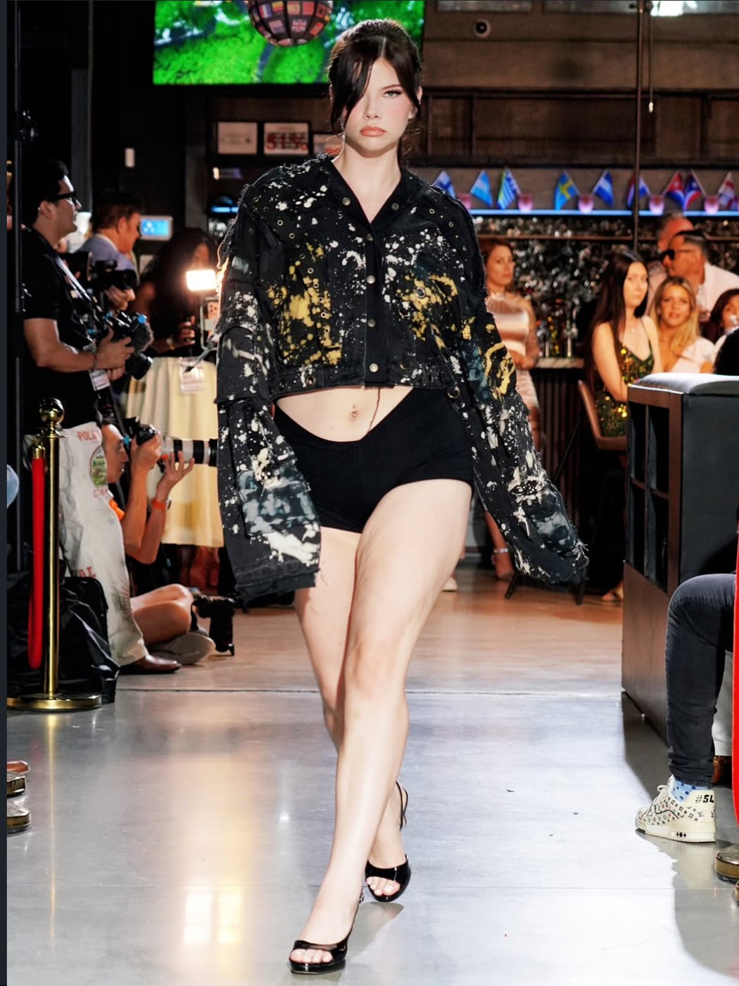 Paint-splattered black denim jacket over black shorts