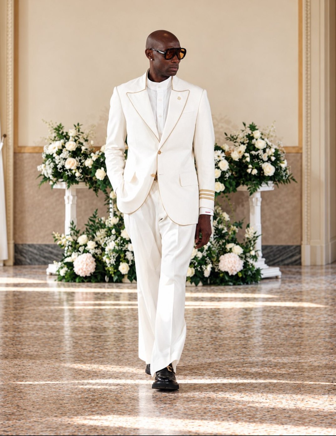 Ivory suit with gold piping, captain cuff stripes and amber shield sunglasses