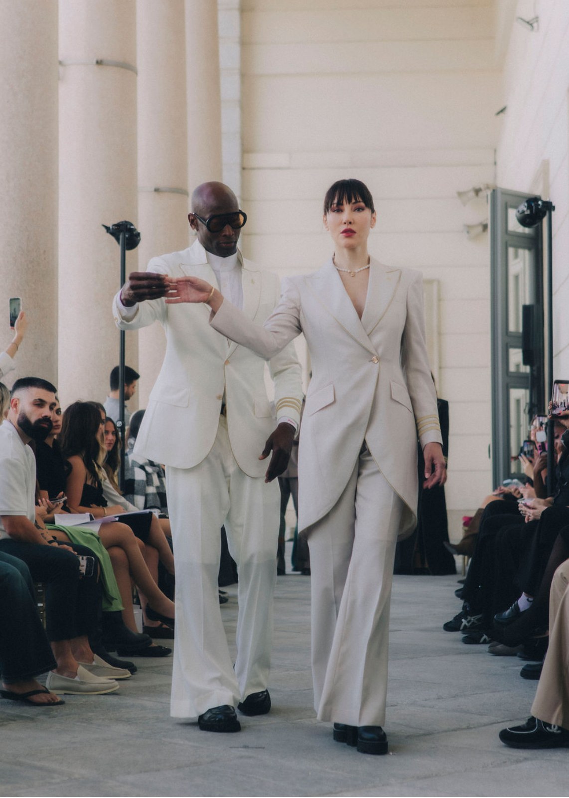 Two models in ivory tailoring walking the runway at Palazzo Clerici