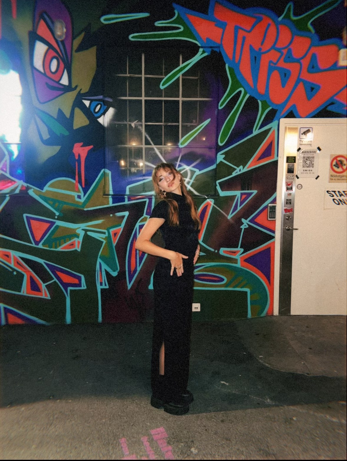 Isabella in a black dress against a graffiti wall