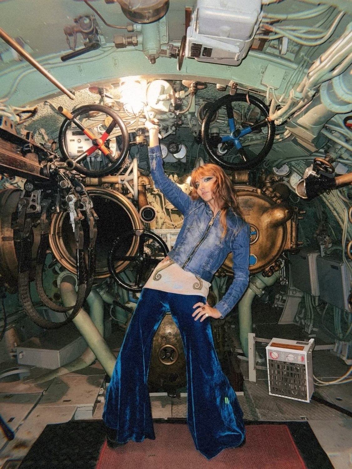 Isabella posing with one hand on the valve wheels in the torpedo room