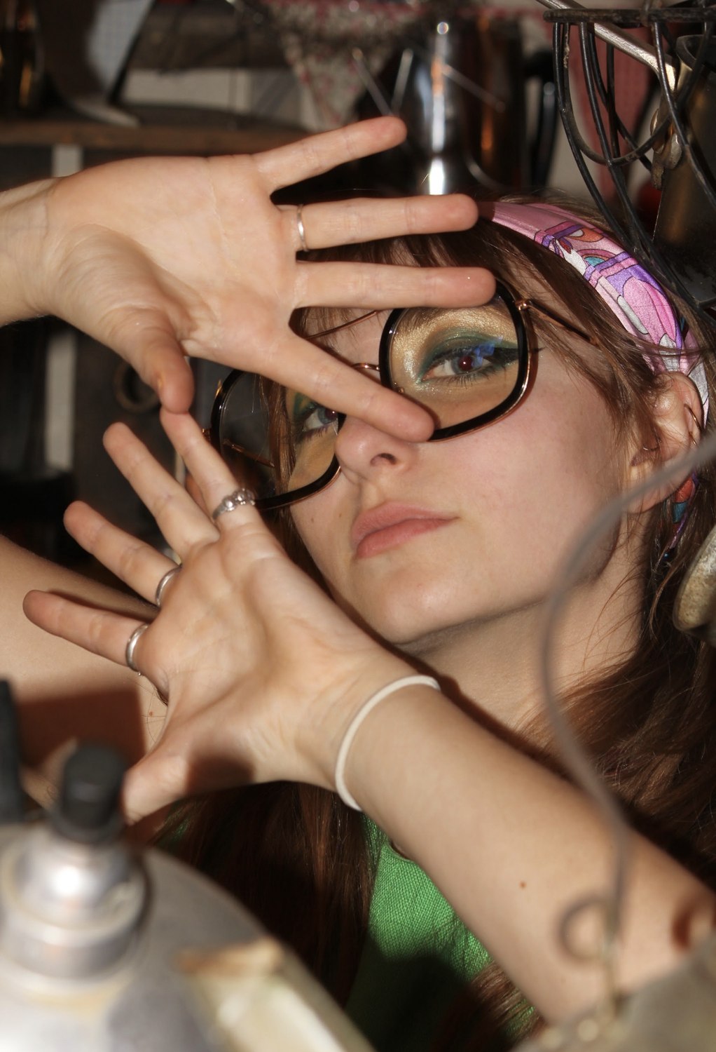 Isabella framing her face with her hands behind oversized glasses