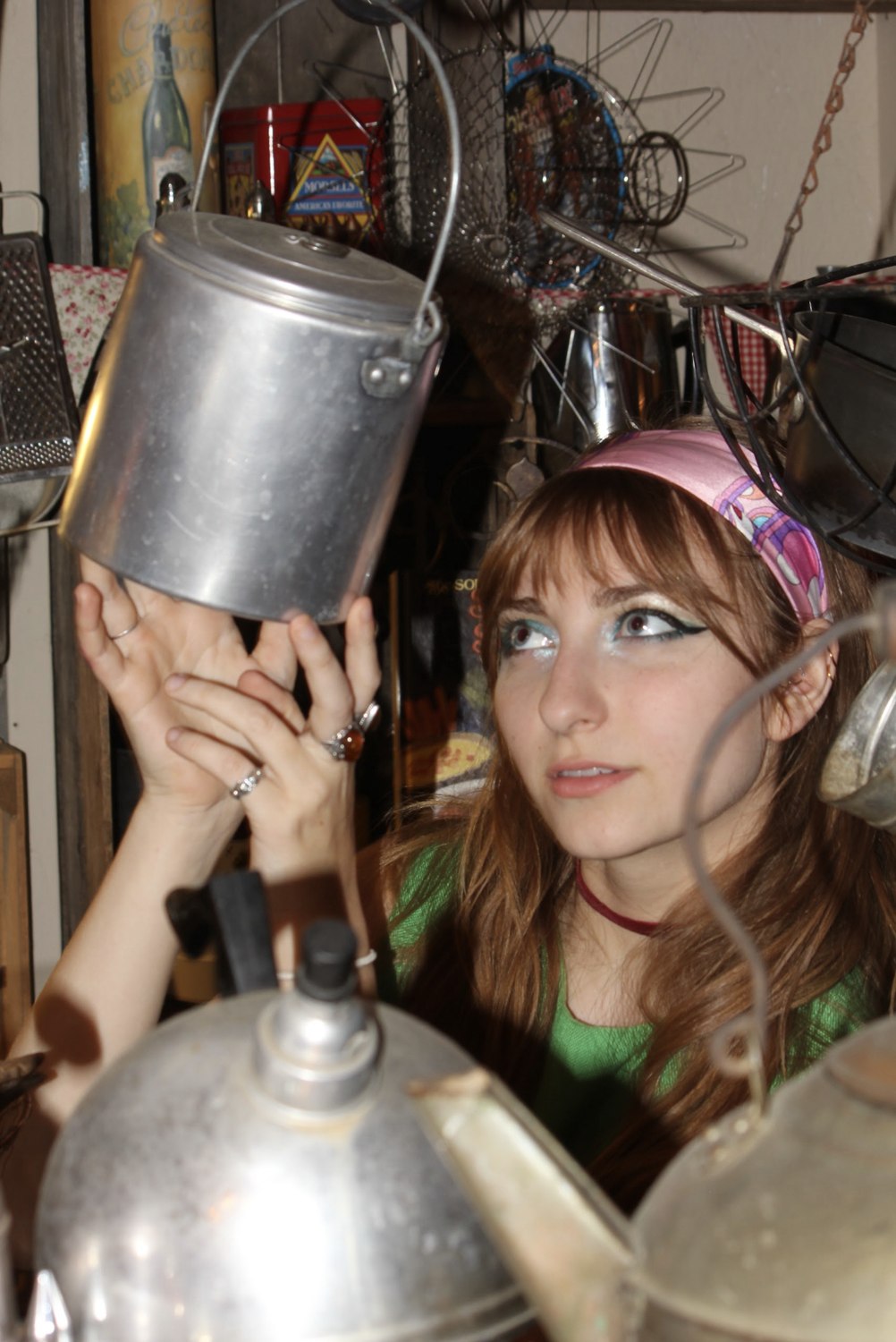Isabella reaching up to a hanging aluminum pot