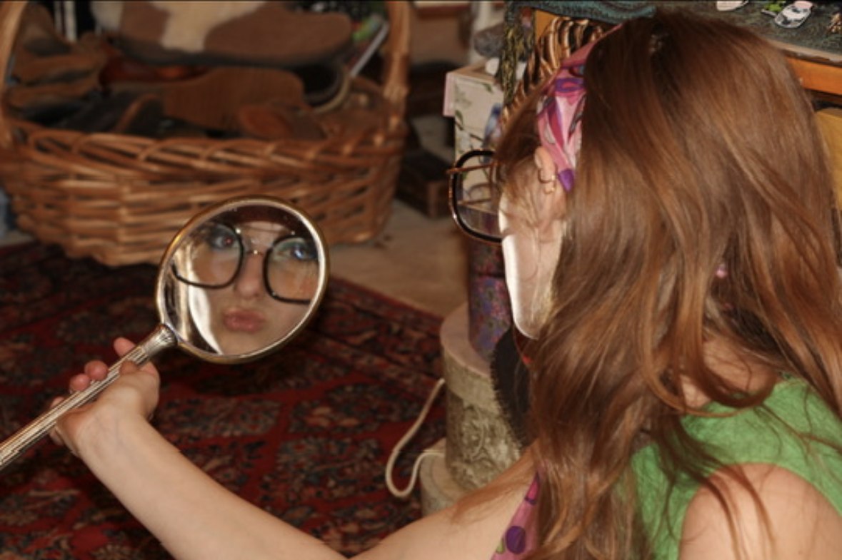Isabella pouting into a hand mirror